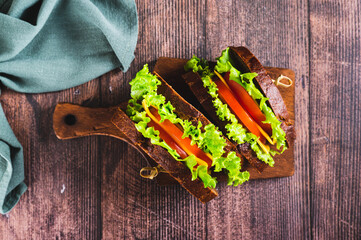 Close up of vegetarian sandwich with tomato, cheese and lettuce on a board top view