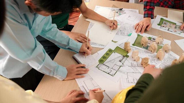 Architect and safety engineer discussion about building construction use blueprint on table with architectural document, measurement tool and wooden block scatter around at modern office. Delineation.