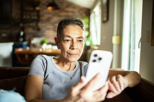 Older woman scrolling on smartphone at home in the living room