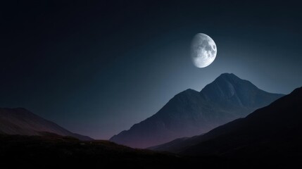 Landscape photograph of a mountain range at night. the sky is dark and the moon is partially visible in the top right corner of the image.