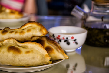 Samosas served on a plate with a teacup and teapot in the background