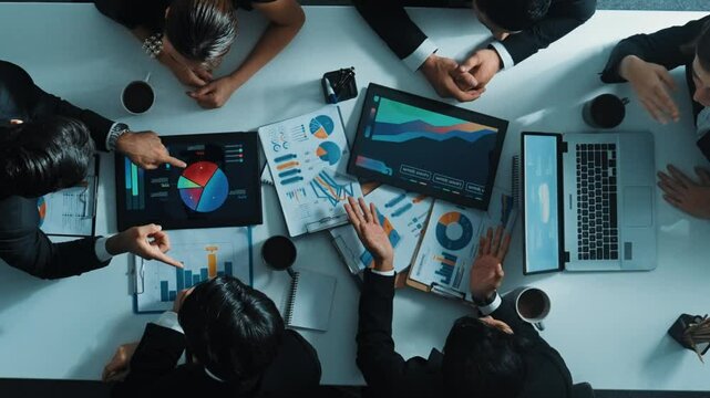Top down aerial view of professional businessman handed out financial statistic to analyst data investment graph. Group of diverse investors brainstorming and planning marketing strategy. Directorate.
