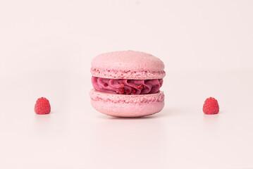 Raspberry macaron with creamy filling on light pink background
