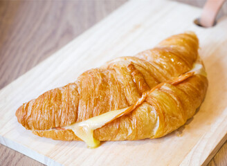 Golden Baked Ham and Cheese Croissant with Melted Cheese on Wooden Board side view