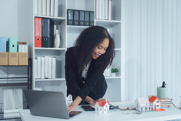 Real Estate Visionary: A poised professional woman in her office setting, focused on a laptop while...