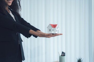 Woman with House Model: A woman holding a miniature house model, representing the concept of...
