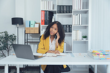 Businesswoman on a Phone Call: A focused businesswoman sits at her modern desk, engrossed in a...