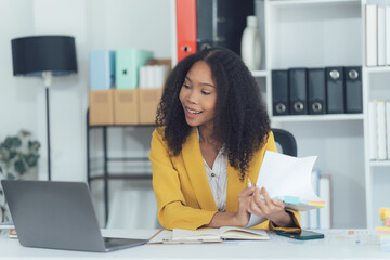 Professional Woman on Laptop at Home Office: A vibrant professional woman conducts remote meeting...