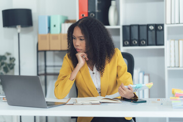 Focused Financial Analysis: A concentrated woman, dressed in a vibrant yellow suit, is deeply...