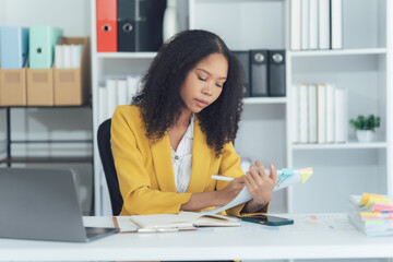 Focused Professional: A dedicated woman meticulously reviews documents in her office, surrounded by...