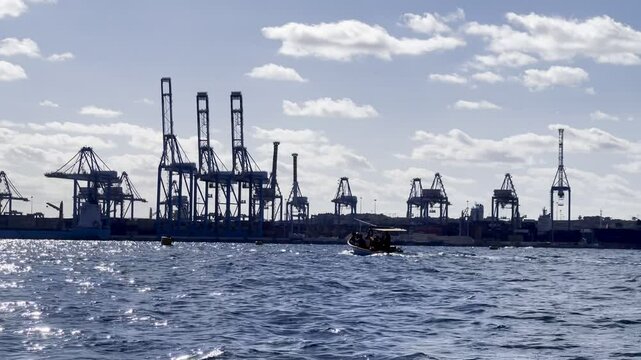 Malta freeport container terminal, birżebbuġa, malta, with moving tourist boat