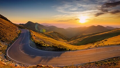 winding road through scenic mountain landscape at sunset with warm yellow sky