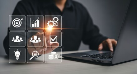 Person interacting with digital icons on a screen near a laptop in a dark setting indoors