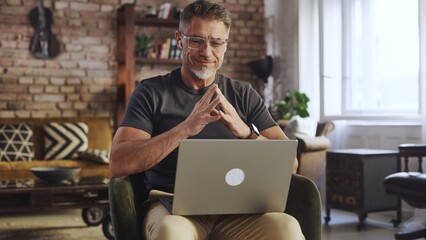 Mature man deep in thought while working on laptop at home. Remote working businessman looking for solution and new ideas. Male entrepreneur managing business online, thinking.