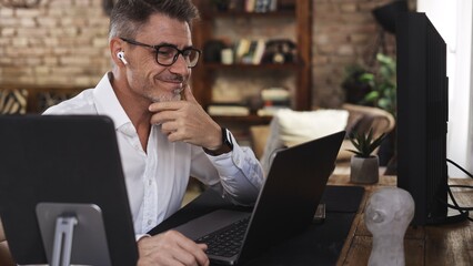 Businessman working from home office typing on laptop using digital tablet. Happy mid adult man in...