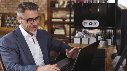 Businessman wearing suit talking in video conference, gesturing, explaining his point of view....