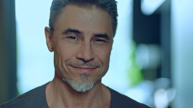 Portrait of a charming man in 50s with friendly, welcoming smile. Happy mid adult, older, senior man with gray hair smiling at home. Blurred background with copy space. - Powered by Adobe