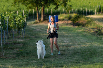 woman running with dog in nature in summer