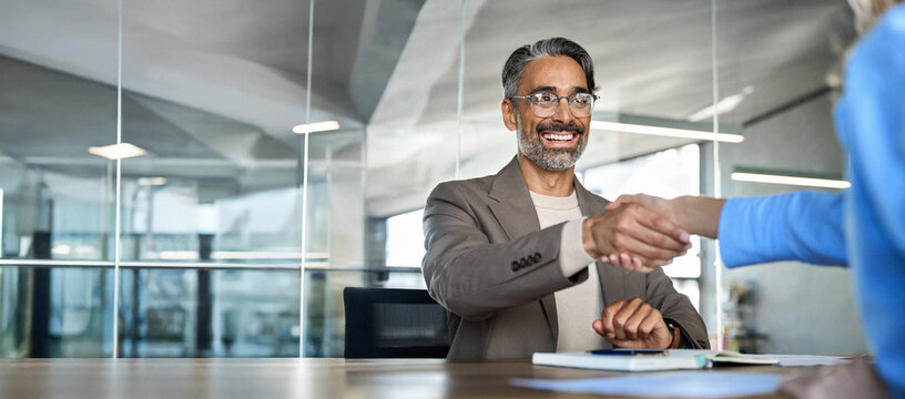 Mature smiling happy professional business man executive, male hr recruiter or bank manager hiring recruit at job interview onboarding corporate office meeting. Handshake with new client concept. - Powered by Adobe