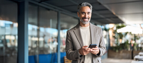 Happy mature older business man executive using mobile cell phone outdoors. Middle aged businessman...