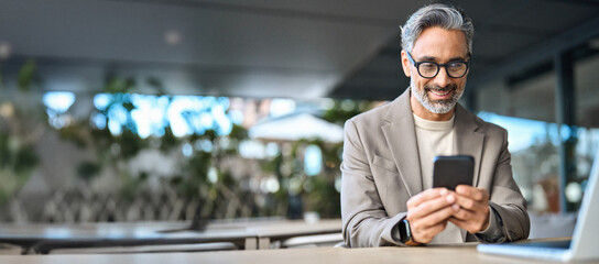 Happy stylish older busy businessman investor holding smartphone looking at cellphone doing banking...