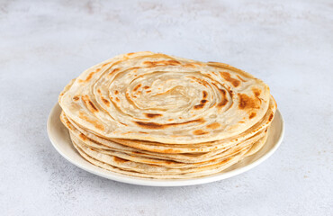 Stack of traditional Indian paratha flatbreads on white background. Indian food.
