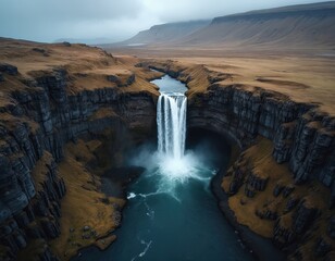 Aerial drone view of Studlafoss waterfall cascading over basalt columns in East Iceland. Icelandic nature landscape from above with moody atmosphere and dramatic rock formations.