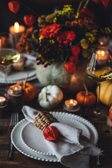 Cozy festive holiday table decor for home family Thanksgiving dinner. Traditional event, elegant natural decoration. Wooden rustic table, countryside style. Burning candles, floral centrepiece pumpkin