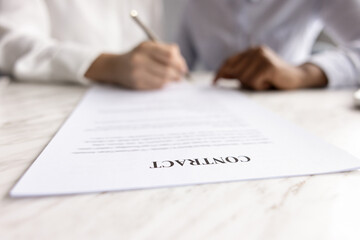 Female places signature on contract paper, close up focus on document title, bank client opening...