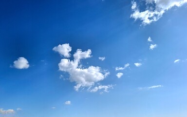 blue sky with clouds.
view of group of white clouds one of which runs away