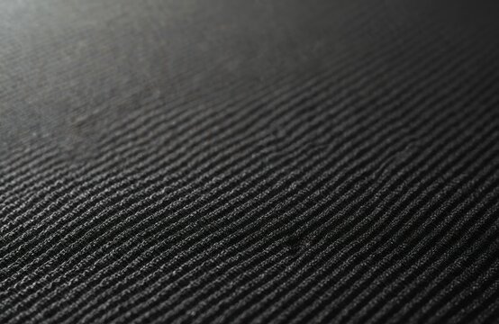 Close-up of speaker grill fabric, dark textured textile with ribbed pattern. Material often used for amplifiers, guitars, audio equipment. Rough surface provides subtle design element for music gear.