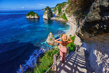 Traveler woman enjoying of amazing landscape of scenic way to Diamond beach during vacation to Nusa Penida Island in Indonesia, travel to touristic beautiful destinations