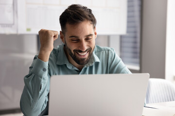 Happy man read great news on laptop with joyful expression, project success, deal closing, or positive work results, enjoy successful completion of task, watching humorous online content during break