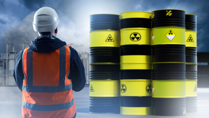 Nuclear industry. Man with back to camera near radioactive barrels. Production polluting...