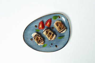 Baked eggplant rolls with cottage cheese on a plate on a white background