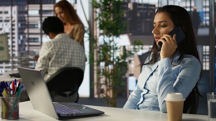 General manager talking about a growth plan on her smartphone, conducting a client call while...