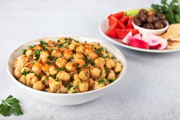Levantine balila or msabah made with warm chickpeas, herbs, olive oil and spices, and fresh vegetables. Breakfast.