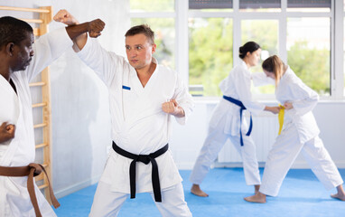 Two men practicing punches during karate classes in the gym