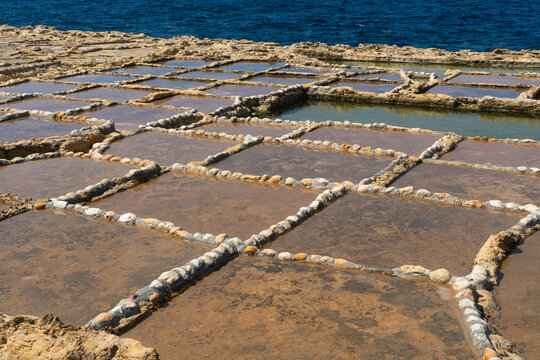 Salt pans and a rocky mountain near Zebbug town at Gozo island, Malta