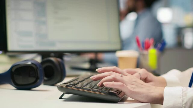 Close up of IT expert coding with AI language model assistance in startup office, using PC. Young admin typing on computer keyboard integrating LLM assistant suggestions into code editor, camera A