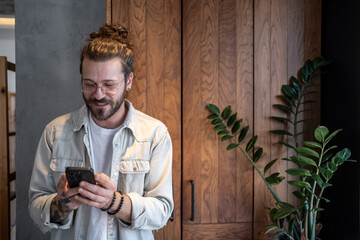 Smiling freelancer using smartphone at home office: modern living and remote work