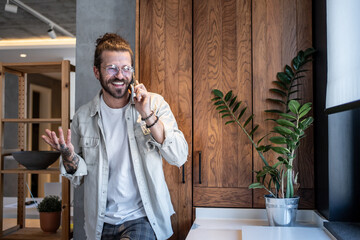 Happy designer talking on the phone in modern office kitchen