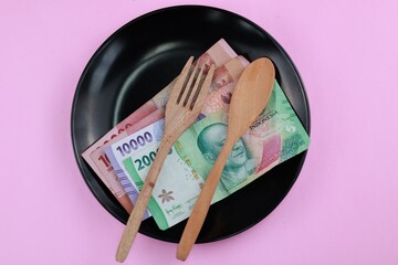 Close up, Indonesia Rupiah bills, with spoon and fork on black plate. prosperisty concept. Business...