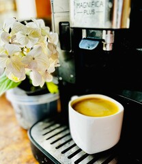 Espresso pouring from a coffee machine into a white cup