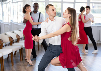 Fototapeta premium Happy woman enjoying impassioned merengue with male partner in latin dance room during party. Social dancing concept