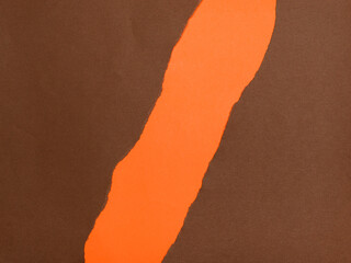 A vibrant orange section is revealed beneath a torn piece of brown paper.