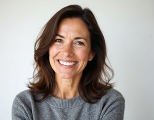 Portrait of cheerful middle-aged brunette woman, around 50 years old, smiling warmly against clean white background. Expression conveys happiness, confidence, perfect for business lifestyle concepts.