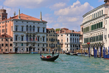 Gondola on Grand Canal in Venice, Italy; gondolier in traditional striped shirt steering through turquoise waters with historic canal buildings in background