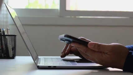 Person using smartphone alongside laptop for login verification, multi-factor authentication, secure access, data protection. Cybersecurity, online banking, digital password, identity, safety business - Powered by Adobe