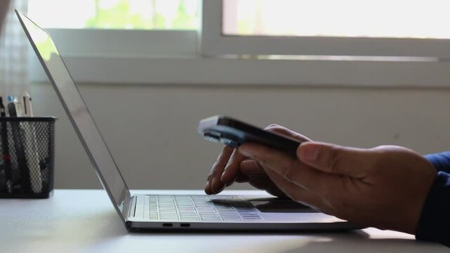 Person using smartphone alongside laptop for login verification, multi-factor authentication, secure access, data protection. Cybersecurity, online banking, digital password, identity, safety business - Powered by Adobe